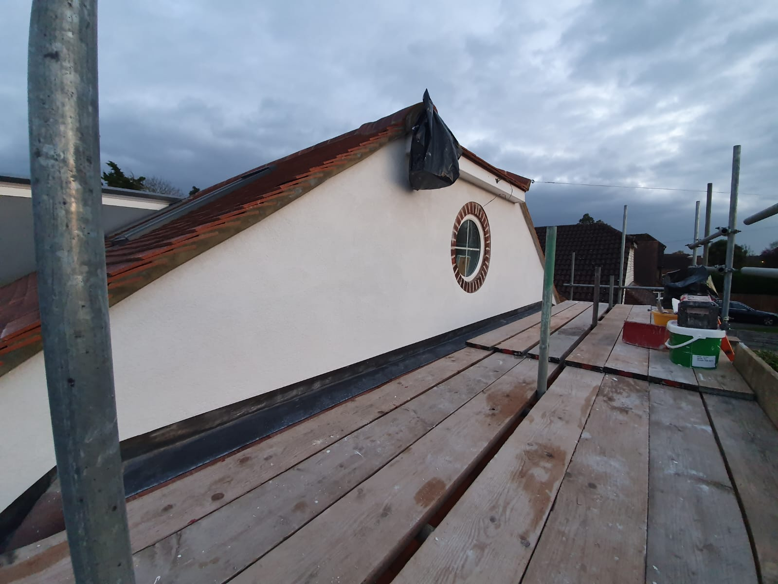 Completed dormer loft conversion exterior with rendered gable, round feature window and new tile roof