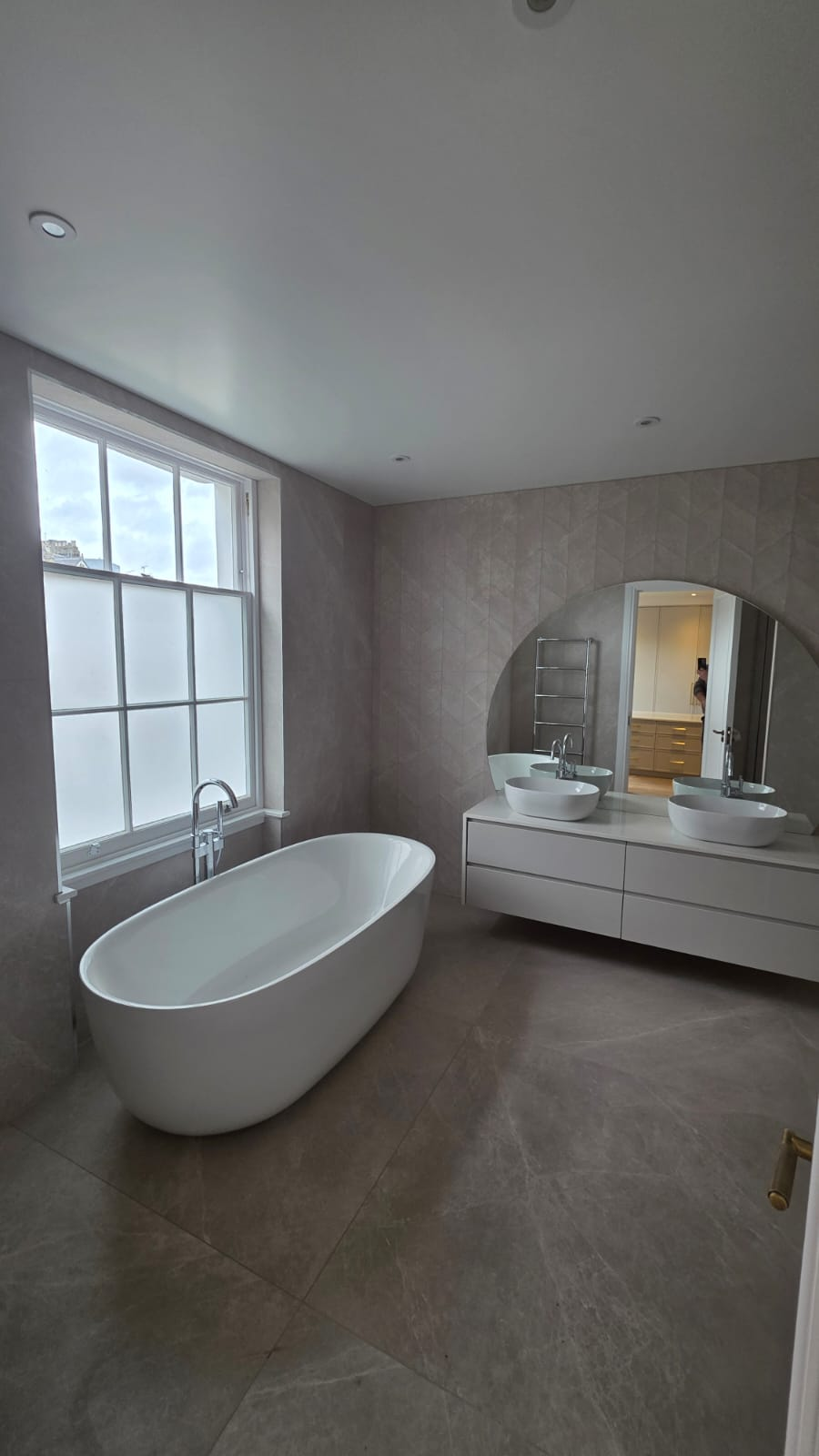 Renovated bathroom with freestanding bath, twin basin vanity and large-format stone tiling
