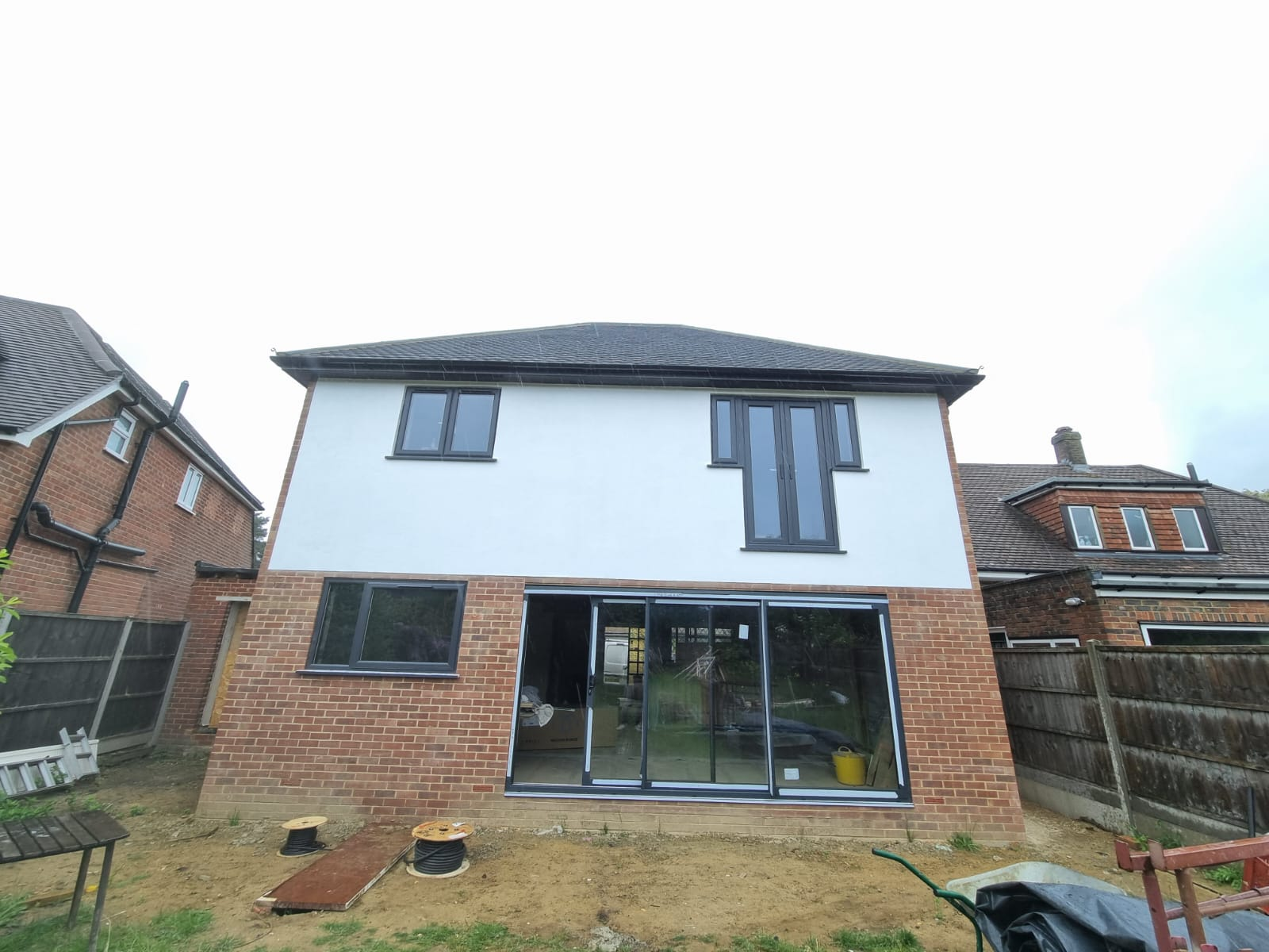 Rear elevation of a renovated house with fresh white render, new brickwork and aluminium bi-fold doors